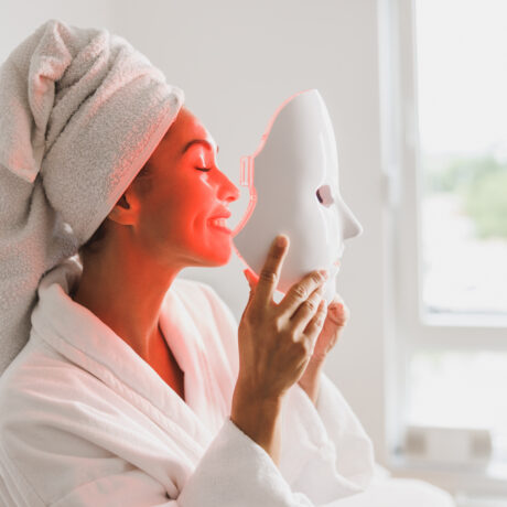 Woman using an LED face mask for anti-ageing and acne treatment