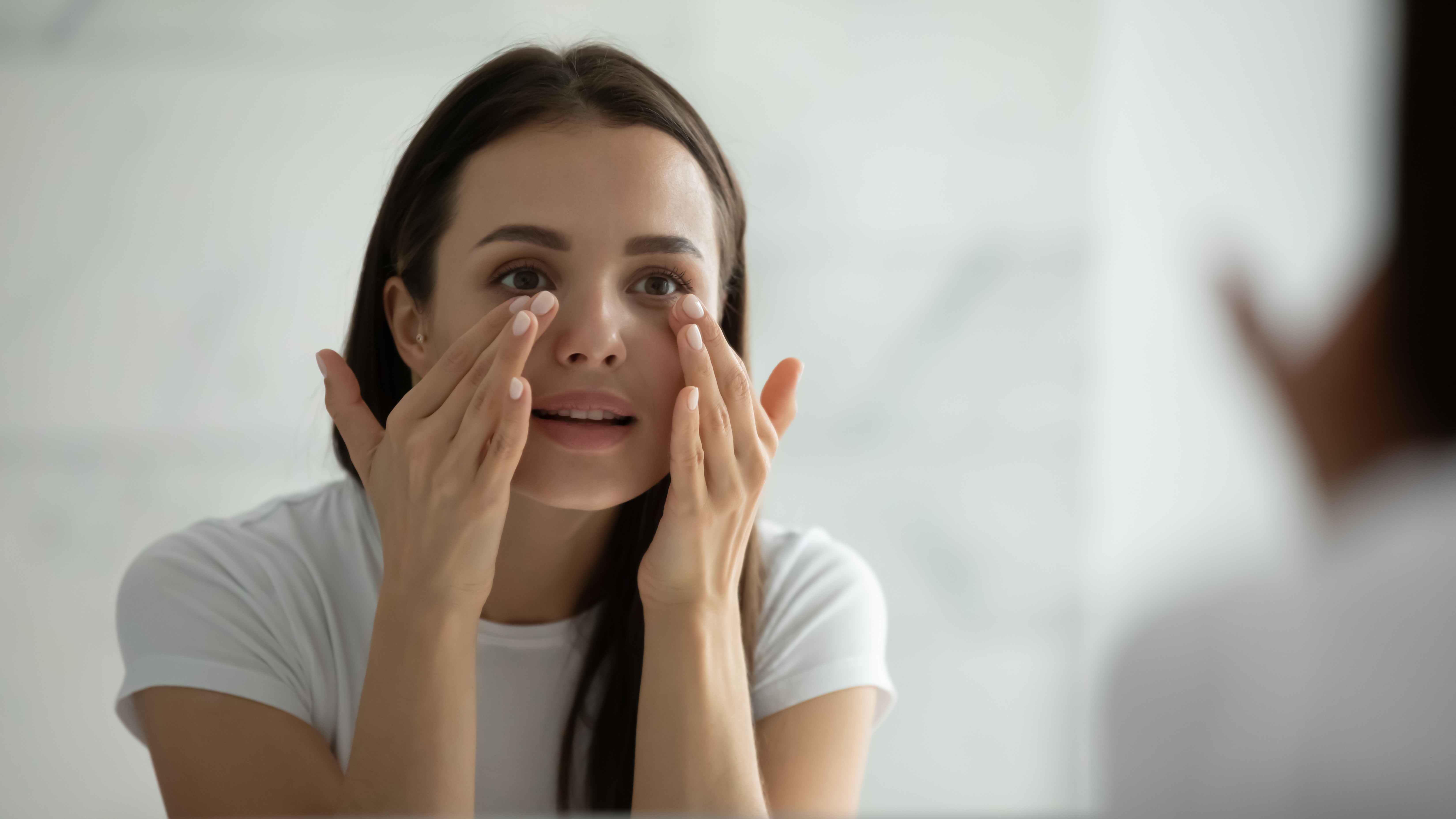 Woman assessing under eye hollows and tear trough area before treatment